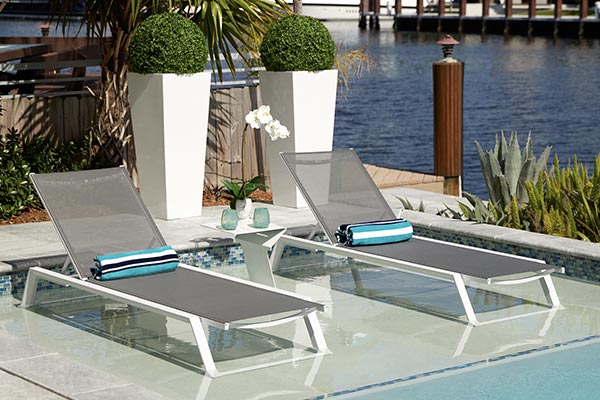 Contemporary outdoor dining furniture set featuring a sleek white table and comfortable grey chairs on a stylish palm leaf rug, ideal for modern patio decor.