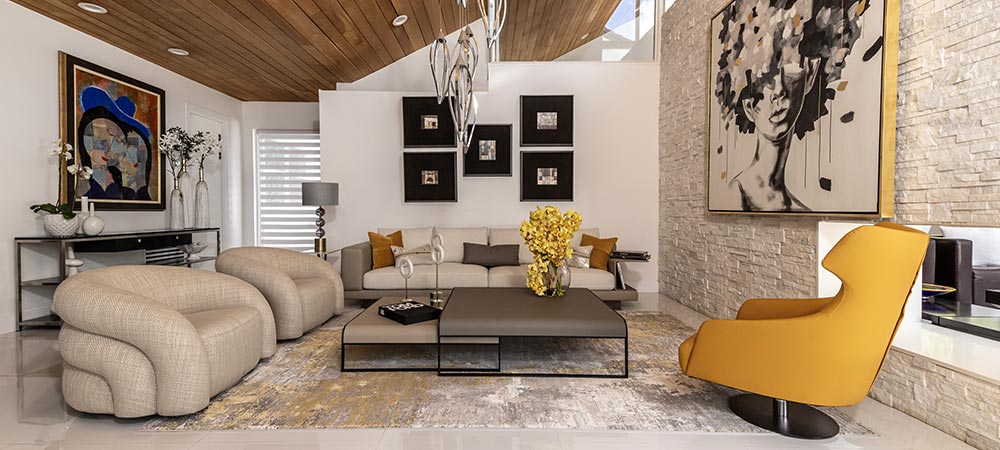 Modern living room with beige sofas, a yellow chair, contemporary art, a large coffee table, and decorative elements in a bright, stylish setting.