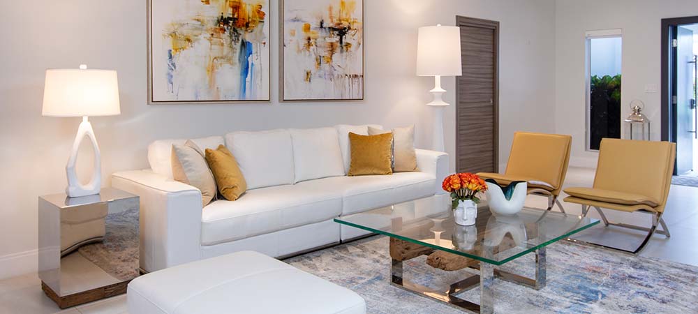 Modern living room with two floor lamps beside a white sofa and glass coffee table, showcasing how lighting enhances the space.