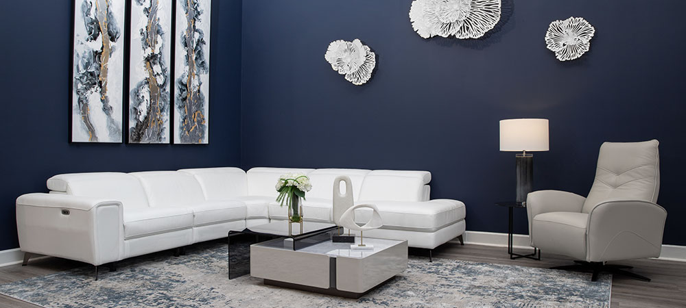 Modern Aparment view of a living room with open windows during the night. A grey Leather sectional and wooden coffee table and teak root side table.