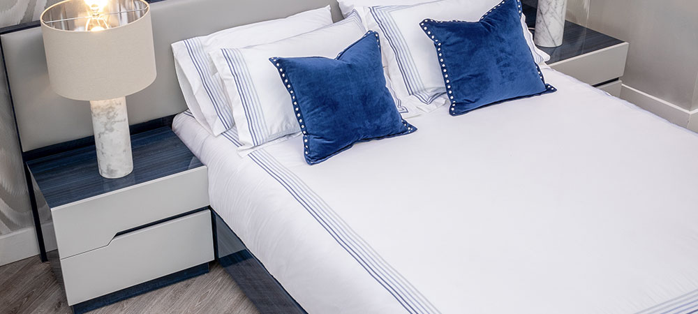 Modern bedroom, a beautiful blue and grey lacquer Nightstand sitting next to a blue lacquer and grey leather bed and a marble table lamp. 