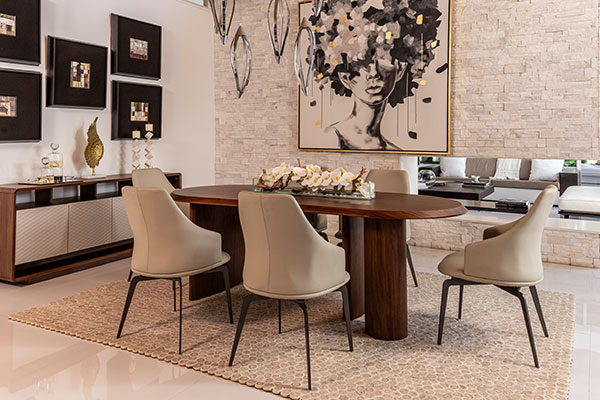 Elegant dining room with oval wood table, beige chairs, and textured stone wall art.